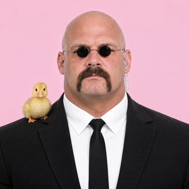 Magnus Brick: bald, horseshoe mustache, tiny round sunglasses, black suit, a duckling on his shoulder